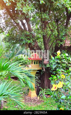 Traditionelles Haus im tropischen Garten, Kambodscha. Kleiner Spirituosenaltar in Form eines Miniaturtempels, der täglich Opfergaben bringt Stockfoto