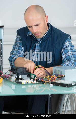 Computeringenieur im Rollstuhl, der an einer kaputten Konsole arbeitet Stockfoto