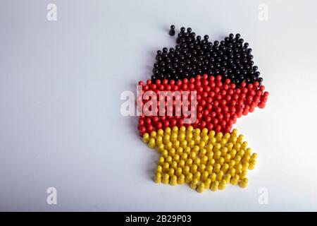 Karte von Deutschland, in Nationalflaggenfarben, mit Holzfigürchen, weißem Hintergrund, isoliert auf Weiß Stockfoto