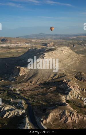 Bunter Heißluftballon, der über die Berge Kappadokiens fliegt - Blick von oben. Stockfoto