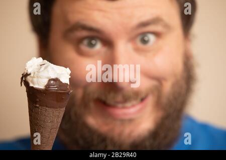 Mann lächelt im Hintergrund eines teilweise gefressenen Eiskegels Stockfoto