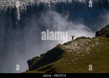 Berühmter Island-Riese-Wasserfall und Frau in Rot gekleidet für die Proportionalität. Stockfoto