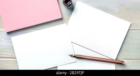 Briefpapier mit einer Tintenflasche und einem Nib-Stift. Leere Grußkarten oder Einladungen, Panoramaaufnahmen über dem Kopf Stockfoto