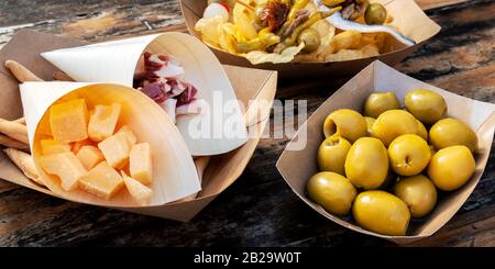 Tapas-Panorama. Käse, Jamon und Oliven auf einem Holztisch in einem Café im Freien Stockfoto