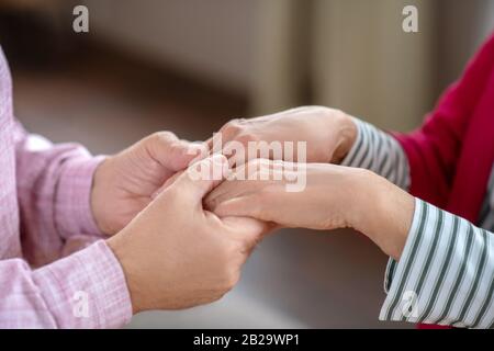 Nahaufnahme der Hände des Mannes, der die Hände der Womanen hält Stockfoto