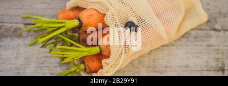Karotte in einer wiederverwendbaren Tasche auf einer stilvollen Holzküche. Zero Waste Concept BANNER, LANGFORMAT Stockfoto