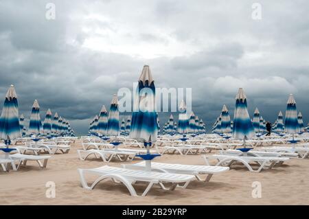 Back-end am Strand. Sonnenschirme wurden geschlossen, der Zauber des schönen Wetters ist gebrochen. Stockfoto