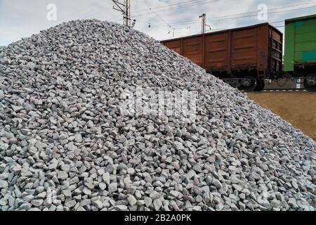 Eisenbahn. Transport von zerkleinertem Stein auf der Schiene. Bahnsteig entladen. Stockfoto