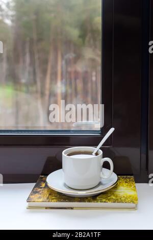 Eine Tasse Tee und ein Buch über die Fensterbank Stockfoto
