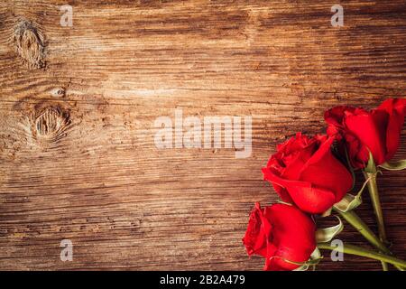 Rahmen mit scharlachroten Rosen für Valentinstag Verzierungen Konzept mit Holzhintergrund. Liebe und Romantik Stockfoto