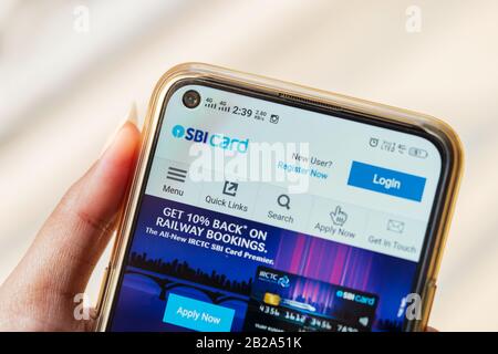 Junge Arbeitsfrau, die Smartphone hält und die offizielle Website der SBI-Karte nutzt oder durchstöbert. SBI Cards & Payment Services IPO-Konzept isoliert auf weißem Bac Stockfoto