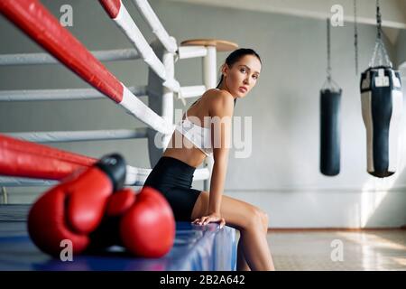Junge schöne Frau entspannen sich nach dem Kampf oder dem Training im Boxring. Sportkonzept Stockfoto