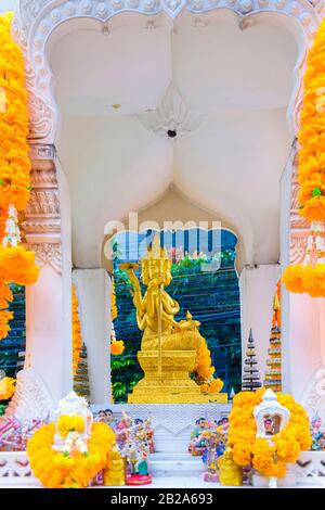 Goldene buddha-statue mit mehreren Facetes in einem Schrein mit orangefarbenen Blumen, Bangkok, Thailand Stockfoto