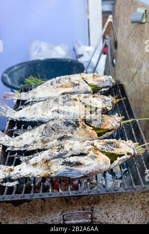 Gesalzene Fische mit Zitronengras, die auf einem Grillgrill in einem Straßenrestaurant, Bangkok, Thailand, gekocht werden Stockfoto