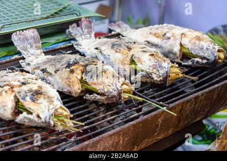 Gesalzene Fische mit Zitronengras, die auf einem Grillgrill in einem Straßenrestaurant, Bangkok, Thailand, gekocht werden Stockfoto