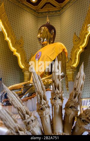 Aus Keramik geschnitzte mehrköpfige Schlange vor einer goldenen Statue des Buddha mit einer Safrangarbe im verzierten Wat Songkhram, Bangkok, Thailand Stockfoto