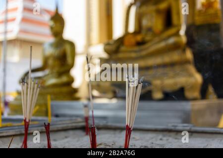 Brennender Weihrauch vor einer goldenen Statue des Buddha, Wat Songkhram, Bangkok, Thailand Stockfoto