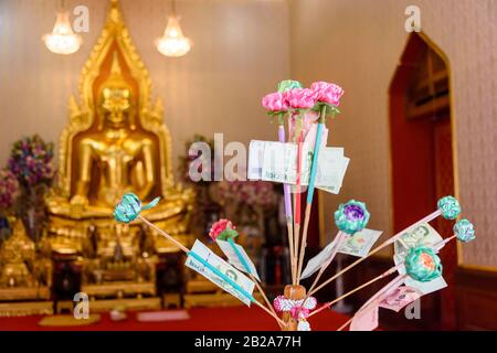 Geschenke von Banknoten vor einer goldenen Statue des Buddha, Wat Songkhram, Bangkok, Thailand Stockfoto