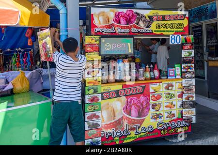 Ein Mann sichert den Sonnenschirm seines "Fried Ice Cream" Stall, Thailand Stockfoto