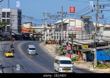 Verkehr auf der Straße mit unordentlichen und unsauberen elektrischen Kabeln, die an einem Strompfosten, Kata, Thailand, hängen Stockfoto