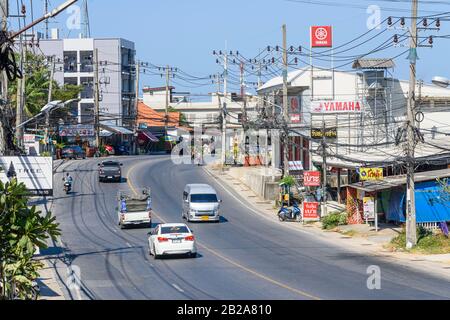 Verkehr auf der Straße mit unordentlichen und unsauberen elektrischen Kabeln, die an einem Strompfosten, Kata, Thailand, hängen Stockfoto