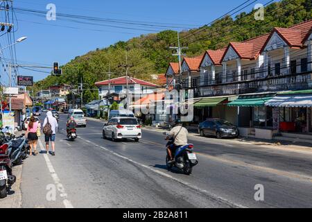 Verkehr auf der Straße mit unordentlichen und unsauberen elektrischen Kabeln, die an einem Strompfosten, Kata, Thailand, hängen Stockfoto