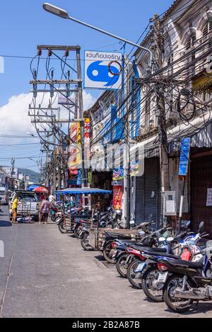 Unordentliche und unsaubere elektrische Kabel, die an einem Strommast in einer Straße, Phuket, Thailand, hängen Stockfoto