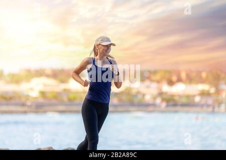 Junge schlanke Läuferin in der Nähe des Meeres morgens joggen. Gesunder Lebensstil Hintergrund mit Kopie Raum Stockfoto