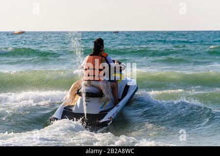 Mann und Frau chinesische Touristen auf einem gemieteten Jetski, der in den Wellen spritzt, Patong Beach, Phuket, Thailand Stockfoto