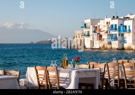 Hellen schönen Nachmittag Blick auf leere Tabellen warten auf den Sonnenuntergang Diners bis entlang des Hafens in der Altstadt von Mykonos, Griechenland Stockfoto