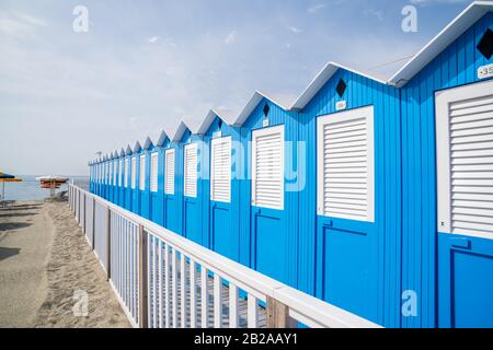 Traditionelle italienische Strandhütten an einem sonnigen Tag, Blaue Strandhütten in Reihen an der Küste angeordnet, Varazze Liguria Italien. Stockfoto