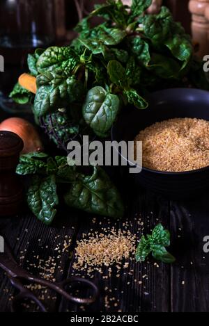 Spinat, Zwiebel und Bulgur auf einem Holztisch Stockfoto