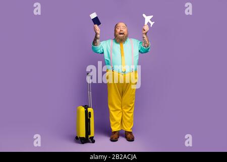 Ganzkörpergröße Blick auf seinen fröhlichen, fröhlichen, reifen Typ, der in den Händen hält Flugzeug Papierkarte Passausfahrt isoliert auf hell lebhaft Stockfoto