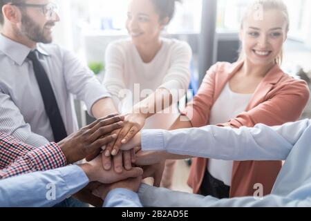 Nahaufnahme der jungen Geschäftsleute, die ihre Hände zusammenlegen. Handstapel. Einigkeit und Teamarbeit. Stockfoto