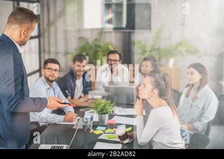 Business Coach. Der Teamleiter unterrichtet die Mitarbeiter bei einem Geschäftstreffen in einem Konferenzraum. Stockfoto