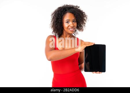 Hübsche Frau mit dunklem Haar zeigt ein neues Tablett und lächelt, Bild isoliert auf weißem Hintergrund Stockfoto