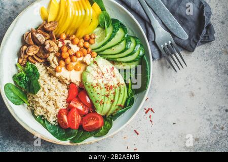 Vegane Mittagsschüssel mit Quinoa, Hummus, Kichererbsen, Avocado, Gemüse und Pilzen. Quinoa-Salat mit Gemüse und Hummus. Stockfoto