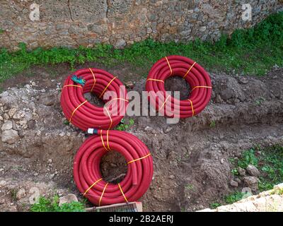 Drei gerollte Rippenröhrchen. Flexible Rohre aus rotem Wellpappe Stockfoto