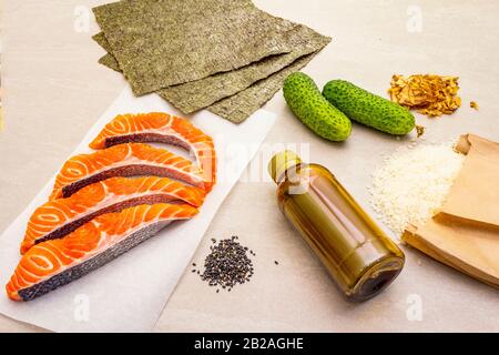 Satz traditioneller Zutaten für japanische Brötchen. Forelle (Lachs), Nori, Gurke, Reis, Bonito Thunfisch Flocken, Sojasoße, Sesamsamen. Die Konce Stockfoto