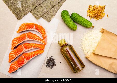 Satz traditioneller Zutaten für japanische Brötchen. Forelle (Lachs), Nori, Gurke, Reis, Bonito Thunfisch Flocken, Sojasoße, Sesamsamen. Die Konce Stockfoto