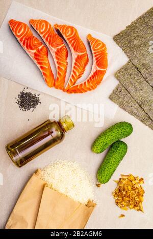 Satz traditioneller Zutaten für japanische Brötchen. Forelle (Lachs), Nori, Gurke, Reis, Bonito Thunfisch Flocken, Sojasoße, Sesamsamen. Die Konce Stockfoto