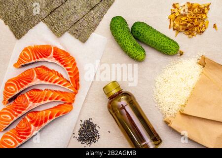 Satz traditioneller Zutaten für japanische Brötchen. Forelle (Lachs), Nori, Gurke, Reis, Bonito Thunfisch Flocken, Sojasoße, Sesamsamen. Die Konce Stockfoto