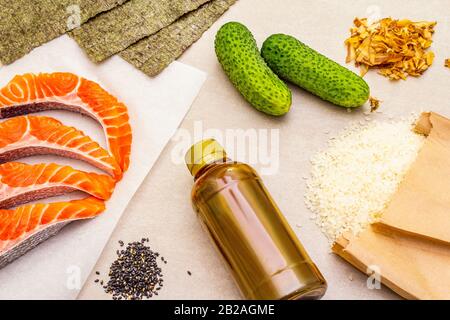 Satz traditioneller Zutaten für japanische Brötchen. Forelle (Lachs), Nori, Gurke, Reis, Bonito Thunfisch Flocken, Sojasoße, Sesamsamen. Die Konce Stockfoto