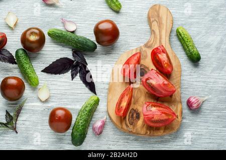 Vegetarischer Salat mit Tomaten, Gurken und Zwiebeln auf dem Küchentisch. Ansicht von oben. Stockfoto