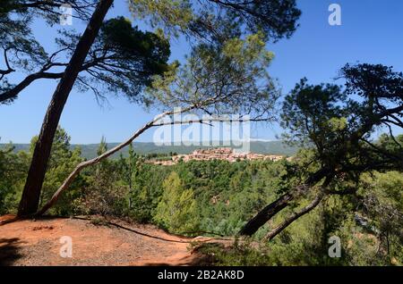 Landschaft mit Ockerfarbenen Auswüchsen und Pine Trees, Die Das Dorf Rousillon im Luberon Regional Park Vaucluse Provence France Umrahmen Stockfoto