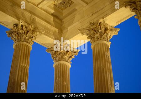 Klassische korinthische Säulen des Maison Carrée oder des römischen Tempels (2AD), Die In Der Abenddämmerung oder in der Nacht Nimes Gard France Beleuchtet werden Stockfoto