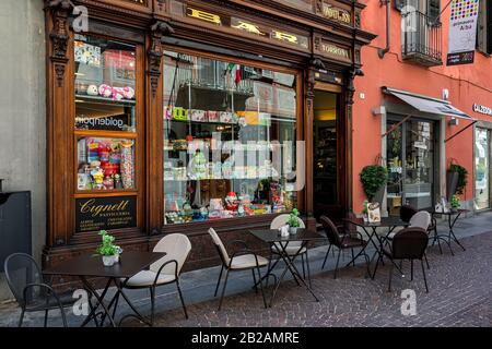 Tische auf der Kopfsteinpflaster Straße vor kleiner Süßwaren - berühmte Familienbäder und Süßwarenladen, die 1878 in Alba, Italien gegründet wurde. Stockfoto