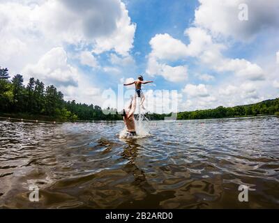 Vater steht in einem See und wirft seinen Sohn in die Luft, USA Stockfoto