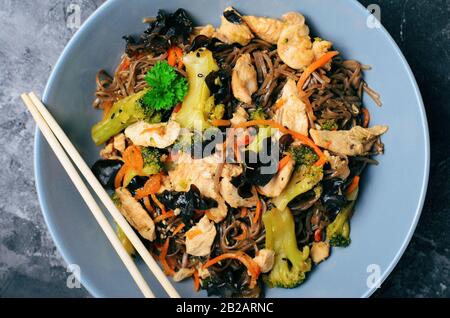 Soba Nudeln mit Huhn und Gemüse, Leckere Mahlzeit vor dunklem Hintergrund Stockfoto