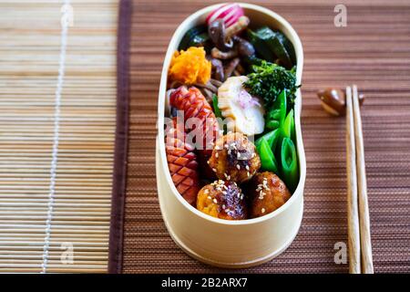 Japanische bento-box mit Fleischbällchen, Wurst und Gemüse Stockfoto